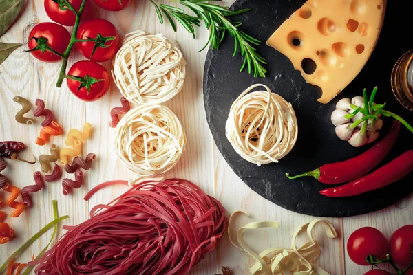 Makarna sebze ve eski bir arka plan üzerinde mutfak aksesuarları ile bir kompozisyon içinde