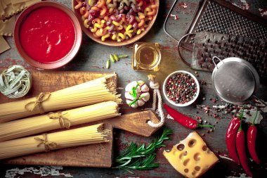 Makarna sebze ve eski bir arka plan üzerinde mutfak aksesuarları ile bir kompozisyon içinde