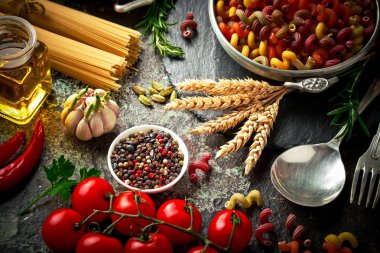 Makarna sebze ve eski bir arka plan üzerinde mutfak aksesuarları ile bir kompozisyon içinde