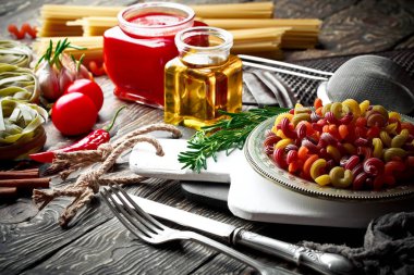 Makarna sebze ve eski bir arka plan üzerinde mutfak aksesuarları ile bir kompozisyon içinde