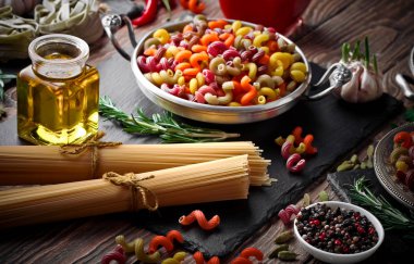 Makarna sebze ve eski bir arka plan üzerinde mutfak aksesuarları ile bir kompozisyon içinde