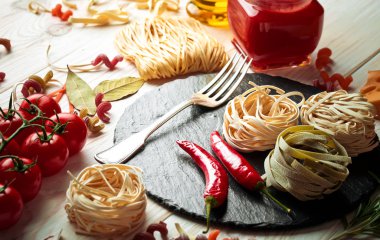 Makarna sebze ve eski bir arka plan üzerinde mutfak aksesuarları ile bir kompozisyon içinde