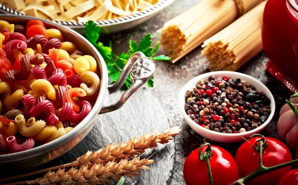 Makarna sebze ve eski bir arka plan üzerinde mutfak aksesuarları ile bir kompozisyon içinde
