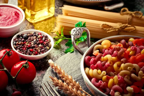 Makarna sebze ve eski bir arka plan üzerinde mutfak aksesuarları ile bir kompozisyon içinde