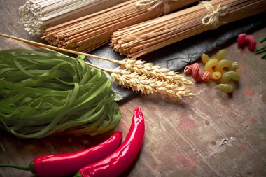 Makarna sebze ve eski bir arka plan üzerinde mutfak aksesuarları ile bir kompozisyon içinde