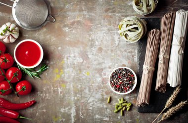 Makarna sebze ve eski bir arka plan üzerinde mutfak aksesuarları ile bir kompozisyon içinde