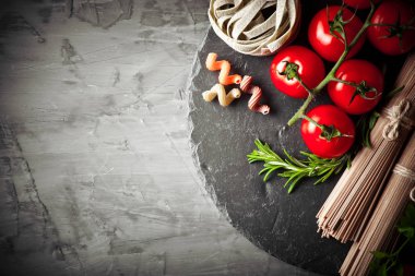 Makarna sebze ve eski bir arka plan üzerinde mutfak aksesuarları ile bir kompozisyon içinde