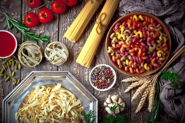 Makarna sebze ve eski bir arka plan üzerinde mutfak aksesuarları ile bir kompozisyon içinde