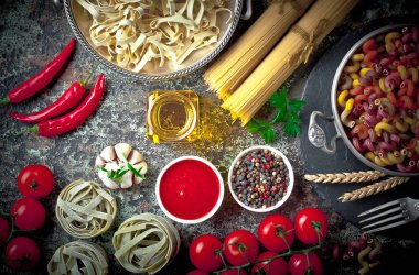 Makarna sebze ve eski bir arka plan üzerinde mutfak aksesuarları ile bir kompozisyon içinde