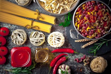 Makarna sebze ve eski bir arka plan üzerinde mutfak aksesuarları ile bir kompozisyon içinde