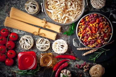 Makarna sebze ve eski bir arka plan üzerinde mutfak aksesuarları ile bir kompozisyon içinde