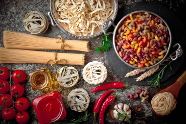 Makarna sebze ve eski bir arka plan üzerinde mutfak aksesuarları ile bir kompozisyon içinde