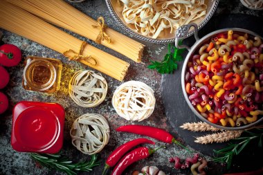 Makarna sebze ve eski bir arka plan üzerinde mutfak aksesuarları ile bir kompozisyon içinde