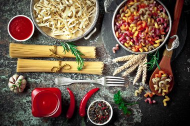 Makarna sebze ve eski bir arka plan üzerinde mutfak aksesuarları ile bir kompozisyon içinde