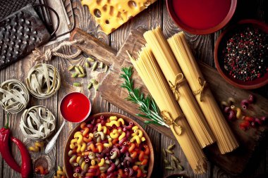 Makarna sebze ve eski bir arka plan üzerinde mutfak aksesuarları ile bir kompozisyon içinde