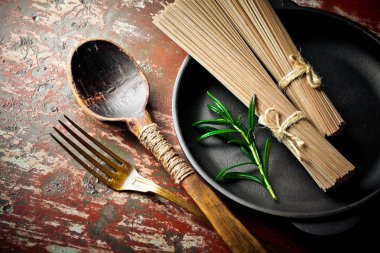 Makarna sebze ve eski bir arka plan üzerinde mutfak aksesuarları ile bir kompozisyon içinde