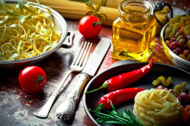 Makarna sebze ve eski bir arka plan üzerinde mutfak aksesuarları ile bir kompozisyon içinde