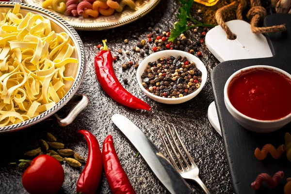 Makarna sebze ve eski bir arka plan üzerinde mutfak aksesuarları ile bir kompozisyon içinde