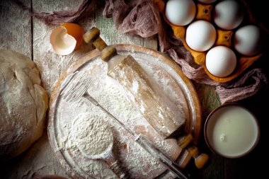 Mutfak aksesuarları ile bir kompozisyon içinde eski bir arka plan üzerinde un ile hamur