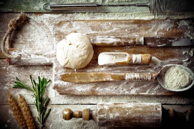 Mutfak aksesuarları ile bir kompozisyon içinde eski bir arka plan üzerinde un ile hamur