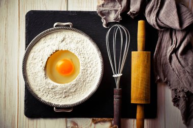 Mutfak aksesuarları ile bir kompozisyon içinde eski bir arka plan üzerinde un ile hamur
