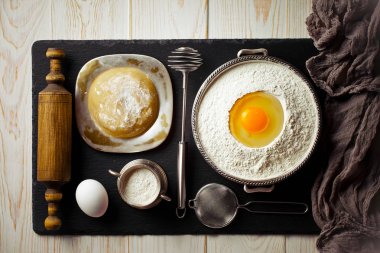 Mutfak aksesuarları ile bir kompozisyon içinde eski bir arka plan üzerinde un ile hamur