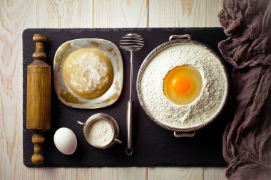 Mutfak aksesuarları ile bir kompozisyon içinde eski bir arka plan üzerinde un ile hamur