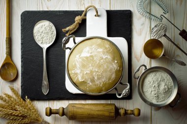 Mutfak aksesuarları ile bir kompozisyon içinde eski bir arka plan üzerinde un ile hamur