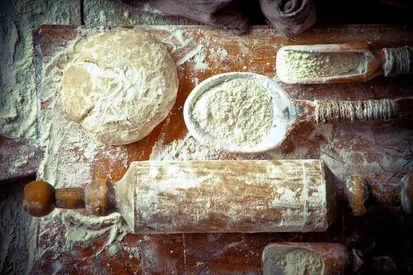 Dough with flour on an old background in a composition with kitchen accessories