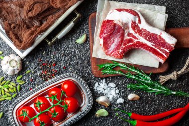 Mutfak masasında aksesuarları pişirme ile bir kompozisyon içinde metalik bir arka plan üzerinde çiğ et