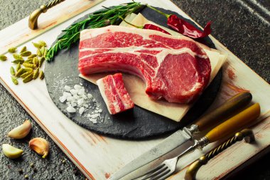 Mutfak masasında aksesuarları pişirme ile bir kompozisyon içinde metalik bir arka plan üzerinde çiğ et