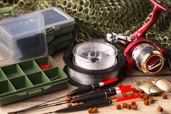 Fishing rods and spinnings in the composition with accessories for fishing on the old background on the table