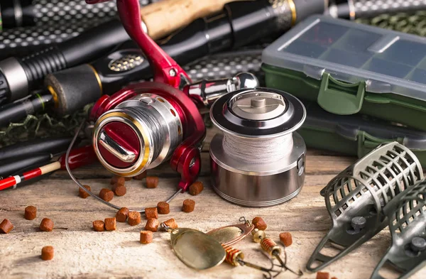 Fishing rods and spinnings in the composition with accessories for fishing on the old background on the table