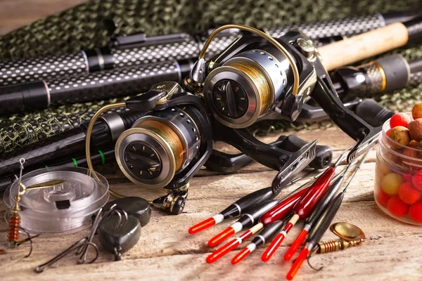 Fishing rods and spinnings in the composition with accessories for fishing on the old background on the table