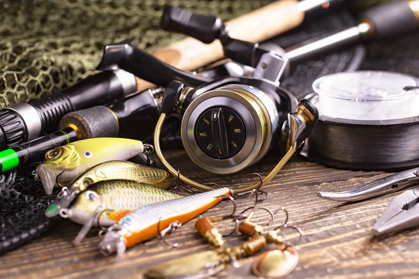 Fishing rods and spinnings in the composition with accessories for fishing on the old background on the table