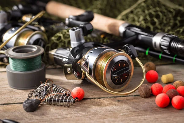 Fishing rods and spinnings in the composition with accessories for fishing on the old background on the table