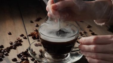 Kahveyi bir kaşıkla karıştırıyorum.