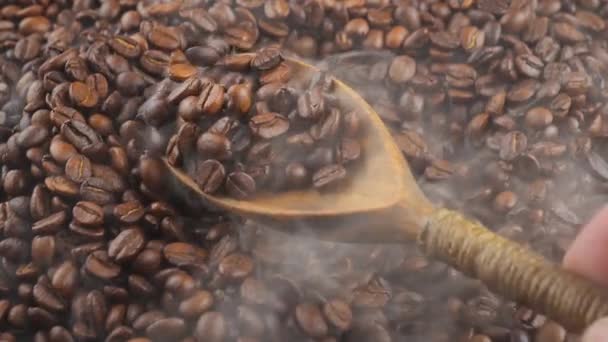 Geröstete Kaffeebohnen werden mit einem Löffel Rauch in einer Pfanne gemischt.