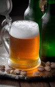 Světlé pivo ve sklenici na stole ve složení s příslušenstvím na starém podkladu