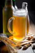 Světlé pivo ve sklenici na stole ve složení s příslušenstvím na starém podkladu