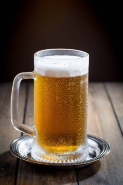 Masadaki bardakta hafif bira kompozisyonu ve eski bir arka planda aksesuar.