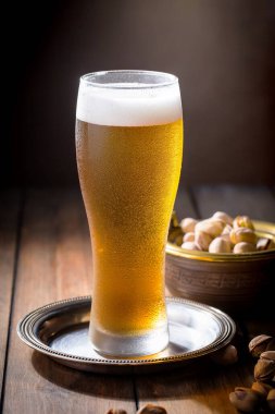 Masadaki bardakta hafif bira kompozisyonu ve eski bir arka planda aksesuar.