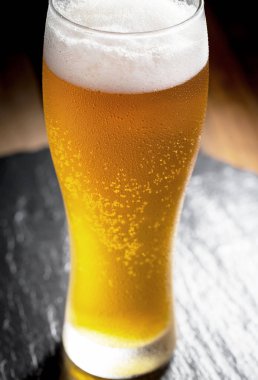 Masadaki bardakta hafif bira kompozisyonu ve eski bir arka planda aksesuar.