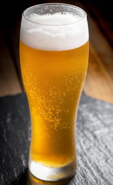 Masadaki bardakta hafif bira kompozisyonu ve eski bir arka planda aksesuar.