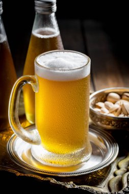 Masadaki bardakta hafif bira kompozisyonu ve eski bir arka planda aksesuar.