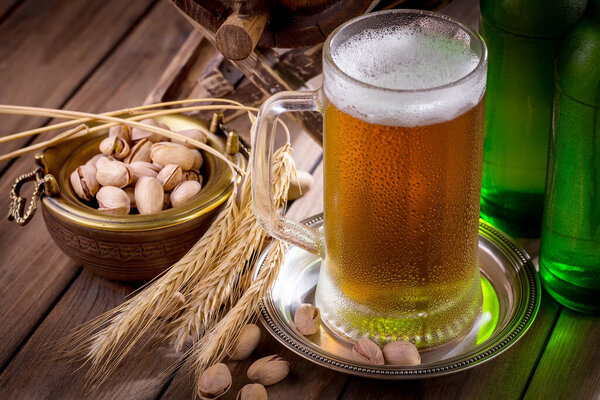 Легкое пиво в стакане на столе в композиции с аксессуарами на старом фоне
