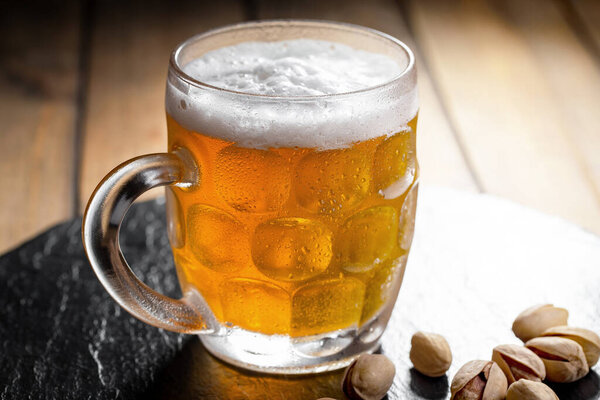 Легкое пиво в стакане на столе в композиции с аксессуарами на старом фоне
