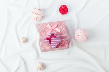 Kurdelelerle süslenmiş iki tane beyaz ipek tuval üzerinde hediye kutuları ve dekoratif toplar. Düşük açıklık, üst küçük kutuya odaklan