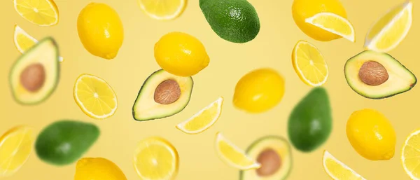 Avokado ve limon (tam, yarım ve dilimlenmiş) bileşenleri karıştırır. Geniş arkaplanda uçan yaratıcı meyveler