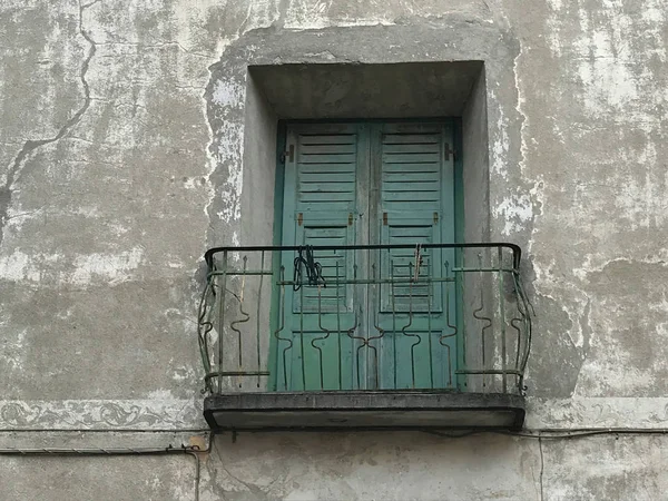Old balcony and green door in old street in Bormio, Italy